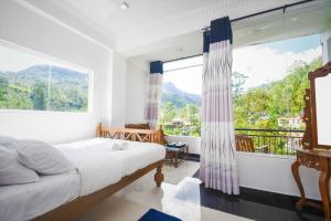 a bedroom with a bed and a large window at Wathsala Inn in Adams Peak