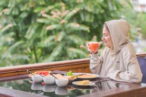 una mujer sentada en una mesa con una copa de vino en Wathsala Inn, en Nallathanniya