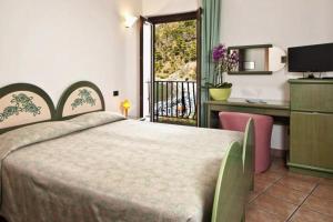 a bedroom with a bed and a desk and a window at Hotel Gabbiano in Maratea