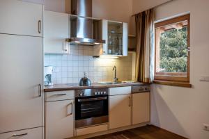 d'une cuisine avec des placards blancs, une cuisinière et une fenêtre. dans l'établissement Ferienparadies Sabina Lärche, à Alpe di Siusi