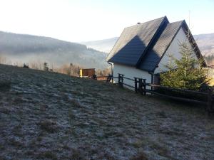 ein kleines Haus auf einem Hügel mit einem Zaun in der Unterkunft Babia Chata in Zawoja