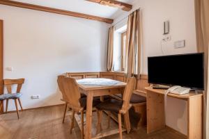 a dining room with a table and a television at Ferienparadies Sabina Compatsch in Alpe di Siusi