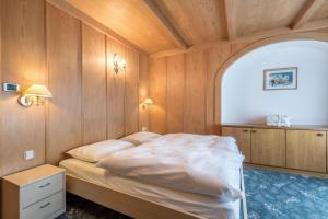 1 dormitorio con 1 cama con pared de madera en Ferienparadies Sabina Spitzbühl, en Alpe di Siusi