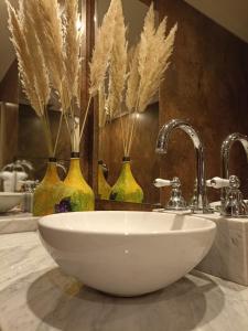 a bathroom with a sink and three vases with feathers at Uspallata Suites in Uspallata