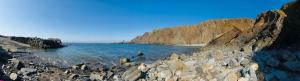 a beach with rocks and water and a mountain at Downe Cottages in Hartland