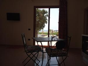tavolo e sedie in una stanza con finestra di Isole Dello Stagnone Apartaments a Birgi Vecchi