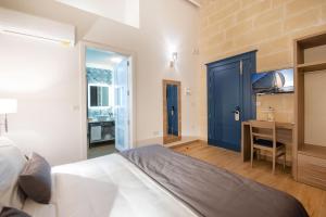 Schlafzimmer mit einem Bett mit blauer Tür und einem Schreibtisch in der Unterkunft Georges Boutique Living in Xagħra