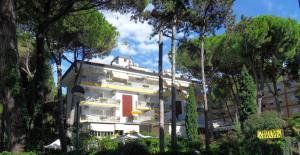 un edificio bianco con alberi di fronte di Hotel Abbazia a Lignano Sabbiadoro