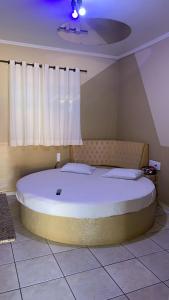 a large white bed in a room with a window at Versat Motel in Barretos