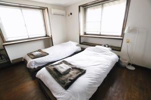 two beds in a room with two windows at Guest house LOOP - Vacation STAY 06208v in Kobayashi