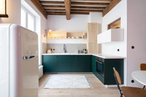 uma cozinha com armários verdes e um frigorífico branco em L'irresistible de Guise em Nancy