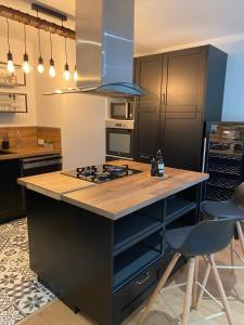 a kitchen with a island with a stove top oven at Le Rocher Appart Hôtel in Valognes