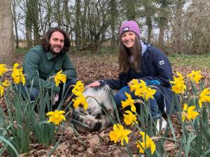 two people kneeling in a field of flowers with a pig at Starry Meadow in Great Yarmouth