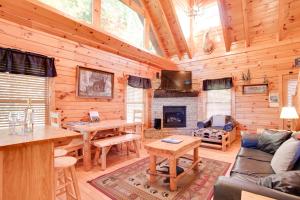 Cabaña de madera con sala de estar con mesa y chimenea en Sleepy Willow Cabin, en Sevierville