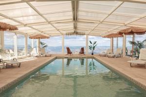 a pool with chairs and umbrellas in a building at Paraíso Douro AL in Lamego