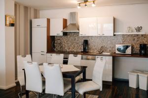 a kitchen with white cabinets and a table and chairs at An der Kastanie in Wiesmoor