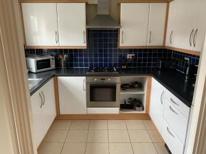 a kitchen with white cabinets and a stove top oven at Entire Family Entertainment Holiday Home - 3 x Floors - Free Parking - Games Room - Private Garden - Workspace and Wifi 112mb - Self Check-in in Ashford