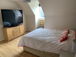 a bedroom with a bed and a flat screen tv at Entire Family Entertainment Holiday Home - 3 x Floors - Free Parking - Games Room - Private Garden - Workspace and Wifi 112mb - Self Check-in in Ashford