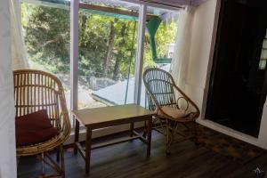einen Tisch und zwei Stühle in einem Zimmer mit Fenster in der Unterkunft Dalhousie Heritage Cottage in Nainital