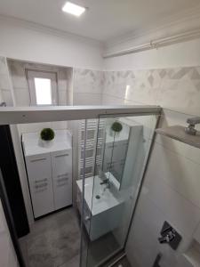bagno bianco con lavandino e specchio di AApartman Exclusive a Pécs