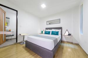 1 dormitorio con 1 cama blanca grande con almohadas azules en Ayenda Bee Hotel, en Pereira