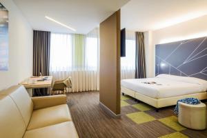 アグラーテ・ブリアンツァにあるMercure Milano Agrate Brianzaのベッドとデスクが備わるホテルルームです。