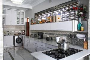 a kitchen with white cabinets and a stove top oven at Muwah Palace villa in Johannesburg