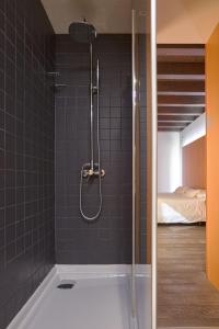 a shower in a bathroom with black tiles at María Pacheco Hotel Boutique in Avila