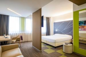 アグラーテ・ブリアンツァにあるMercure Milano Agrate Brianzaのベッドとデスクが備わるホテルルームです。