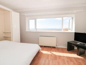 - une chambre avec un lit et une grande fenêtre dans l'établissement Flat 30, à West Bay