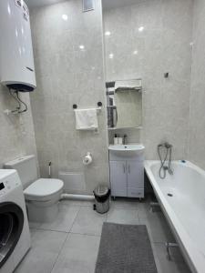 y baño con aseo, lavabo y lavadora. en Апартаменты Жасмин, en Karagandá