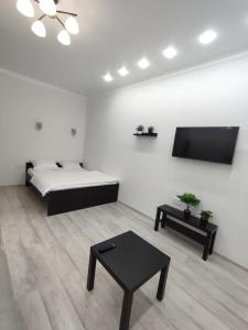 Habitación blanca con cama y mesa en Апартаменты Жасмин, en Karagandá