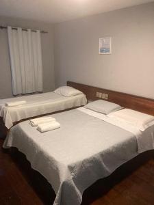 two beds in a room with white sheets and towels at Pousada Lá Na Praia in São José da Coroa Grande