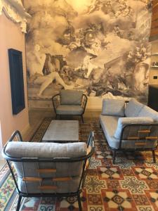福贾Residenze Romano Ristorante & Spa - albergo diffuso - RED的一间房间,配有三把椅子和墙上的绘画