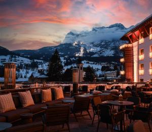 
a restaurant with tables and chairs in front of a mountain range at Grand Hotel Savoia Cortina d'Ampezzo, A Radisson Collection Hotel in Cortina dʼAmpezzo
