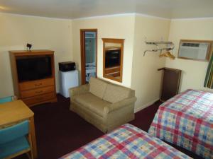 a hotel room with a bed and a couch and a television at Tower Motel in Green Bay