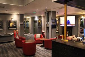 a lobby with red chairs and a tv and a bar at Devoncove Hotel Glasgow in Glasgow