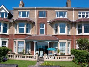 a large brick house with an umbrella in the yard at Weymouth Bay Apartment C in Weymouth