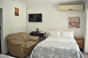 una camera con letto, sedia e televisore di Iceberg Venue, Guest Lodge & Events place a Benoni