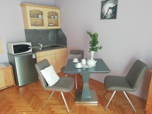 a small kitchen with a table and two chairs at Szilvia apartman in Harkány