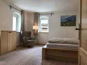 a bedroom with a bed and a chair and two windows at Schöna Urlaub in Schöna