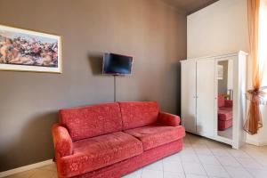 un divano rosso in un soggiorno con TV di Stop & Sleep Bergamo a Bergamo