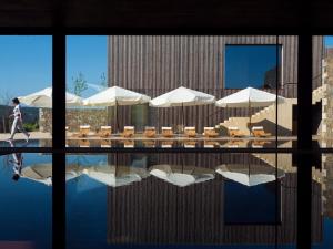 uma pessoa a andar à beira de uma piscina com guarda-sóis e mesas em Monverde - Wine Experience Hotel - by Unlock Hotels em Amarante