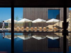 a person walking by a pool with umbrellas and tables at Monverde - Wine Experience Hotel - by Unlock Hotels in Amarante +144 photos