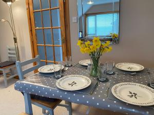 ein Tisch mit Tellern und einer Blumenvase darauf in der Unterkunft Enegar Accommodation in Stromness