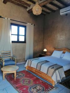 a bedroom with a bed and a chair and a window at Gîte Ait lmaalam chez Ahmed in Skoura