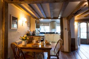 沙夫倫沃登的住宿－Miller Cottage a luxury 1550's cottage in the Historic centre of Saffron Walden，一间带木桌和椅子的厨房以及一间用餐室