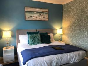 a bedroom with a bed with blue walls and two lamps at The Drey in Sandown