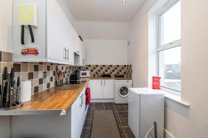 a kitchen with white cabinets and a washer and dryer at Two bedroom holiday apartment Colwyn Bay in Colwyn Bay