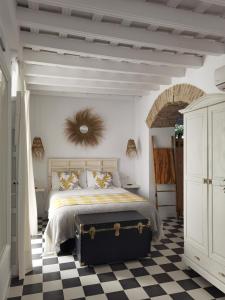 a bedroom with a bed with a black suitcase on a checkered floor at Casa del Sacramento - CASITA CON ENCANTO in Medina Sidonia